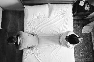 interracial couple sitting back back bed